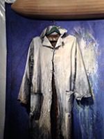 Old coat hanging against blue backdrop
